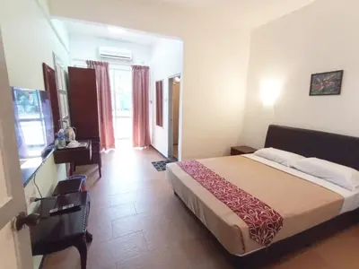 a bedroom with a bed and a desk in a room at Collection O Analisa Beach Resort in Pangkor