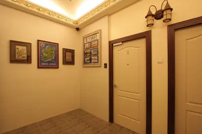a hallway with a white door and some pictures at Shamrock Guest House II in Ipoh