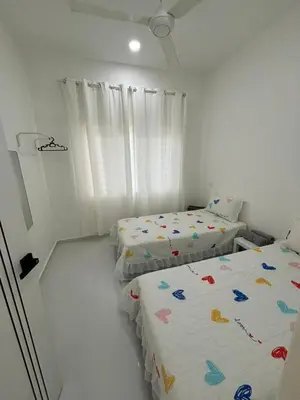 two beds in a room with white walls at Homestay Bajet Cikgu Amin in Bagan Serai