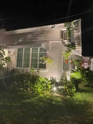 a white house with windows and plants in the yard at Heritage Cottage in Georgetown in Jelutong