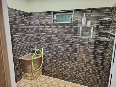 a bathroom with a shower with a large tile wall at Sri MaLati Homestay and Event Space in Balik Pulau