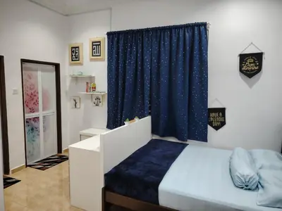 a bedroom with a bed and a blue curtain at Sri MaLati Homestay and Event Space in Balik Pulau