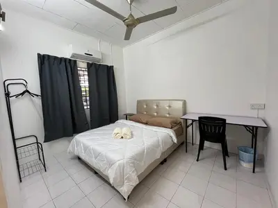 a bedroom with a bed and a table and a table at Green Woody Homestay in Ipoh