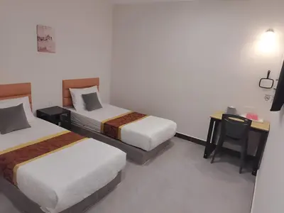 a hotel room with two beds and a desk with a chair at CMN Hotel & Homestay in Sungai Petani