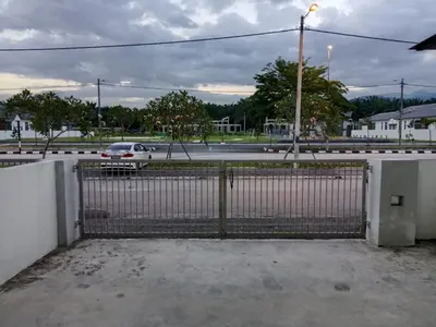 a gate with a car parked in a parking lot at Double H Homestay in Tanjung Rambutan