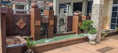 a building with a fountain in front of a house at Homestay Santai Bertam in Kepala Batas