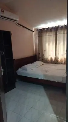 a bedroom with a bed and a window with curtains at Impiana Homestay in Kampong Kawak