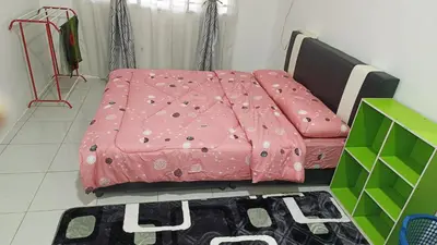 a pink comforter on a bed in a room at Homestay Kak Rose 2 Kuala Lipis in Kampong Temperah