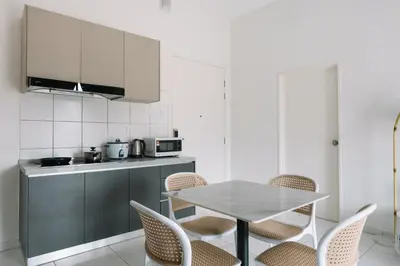 a white kitchen with a table and chairs at NEW The Sun 3Bedrooms 10pax 2CP in Bayan Lepas
