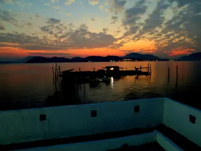 a sunset on a lake with a boat in the water at Pangkor Fish House in Pangkor