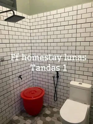 a bathroom with a toilet and a red bucket at FF Lunas Homestay in Lunas