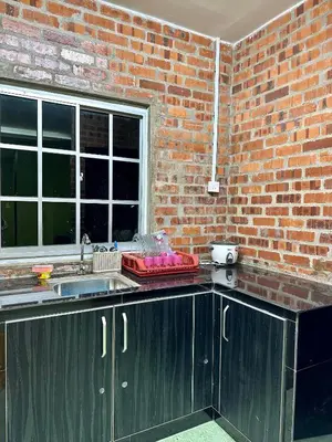 a kitchen with a sink and a brick wall at Bola-Bola DHomestay in Kepala Batas