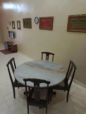 a table with two chairs and a clock on a wall at Airis Homestay Bertam Perdana in Kepala Batas