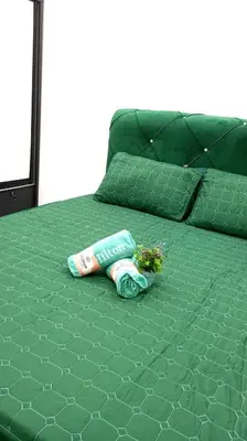 a green bed with two water bottles and flowers on it at Affan Homestay in Seri Iskandar
