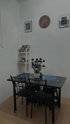 a black table and chairs with a vase of flowers on it at Homestay KakCik Ah in Kepala Batas