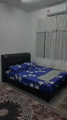 a bedroom with a bed with a blue comforter and a window at Homestay KakCik Ah in Kepala Batas