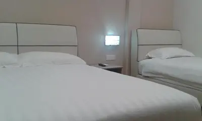 a bedroom with two beds with white sheets and a window at Welcome Inn GM in Gua Musang
