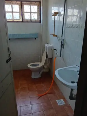 a bathroom with a toilet and a sink and an orange hose at Homestay Jannati Bandar Baru Putra Ipoh in Ipoh