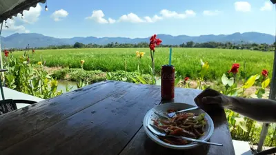 a bowl of food on a table with a field of flowers at Love UU Garden - Paddy View Stay with Bicycle Ride in Balik Pulau