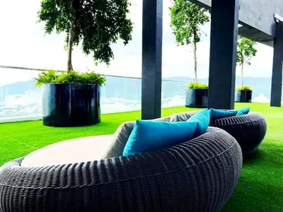 a wicker couch with blue pillows sitting on the grass at a29 seaview luxury 3BR-10PAX URBAN NETFLIX in Jelutong