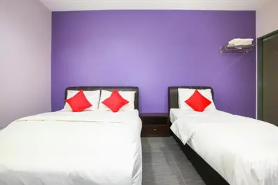 two beds with red and white pillows in a room at De Hotel in Teluk Intan