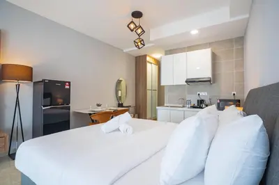 a bedroom with a white bed and a kitchen at Wyndham Garden Suites IPOH ICC in Ipoh
