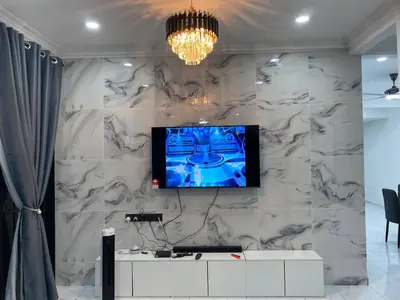 a living room with a tv on a marble wall at Rania Homestay Tasek Gelugor in Padang Chempedak