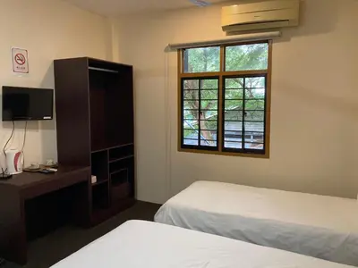a hotel room with two beds and a window at De Village Lodge in Balik Pulau