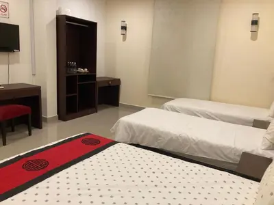 a hotel room with two beds and a television at De Village Lodge in Balik Pulau