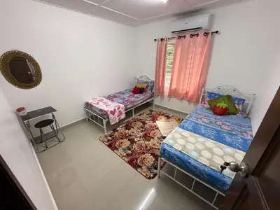 a small room with two beds and a window at Teratak Laman Bari in Sekincan