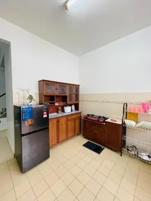 a kitchen with a black refrigerator and wooden cabinets at Bayan Homestay Bayan Lepas Penang in Bayan Lepas