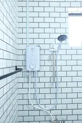 a shower in a bathroom with a white brick wall at Aeden Villa Roomstay & Homestay in Kuala Kangsar