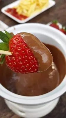 a spoon with a strawberry in a bowl of chocolate at Astana D'Cameron Homestay in Brinchang