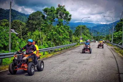a group of people riding motorcycles down a road at Kabinstay suasana dusun in Kampung Lubuk Buaya