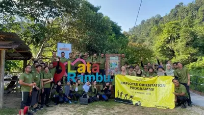 a group of people posing for a picture with a banner at Kabinstay suasana dusun in Kampung Lubuk Buaya