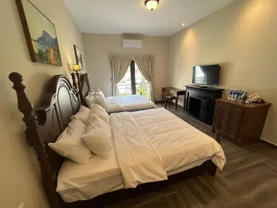 a bedroom with a bed with white sheets and a television at The Ranch in Ipoh