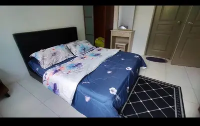 a bed with a blue comforter in a room at Ummu's homestay in Tanah Rata