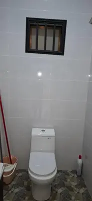 a white bathroom with a toilet and a window at D'Intan Villa Gerik in Gerik