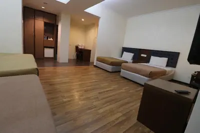a hotel room with two beds and a wooden floor at Iris House Hotel Cameron Highlands in Brinchang