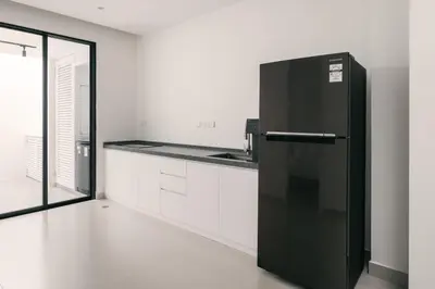 a black refrigerator in a kitchen with white cabinets at Romantic Rooftop Jacuzzi Villa with Sunset Views in Jelutong