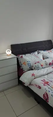 a bed with a black headboard and pillows and a clock at DeRose Homestay, Pekan Ipoh in Ipoh