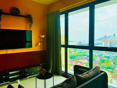 a living room with a couch and a large window at Deluxe Suites with Infinity Pool, Kids' Pool & Sea in Jelutong