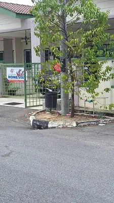 a tree in front of a building with a fence at A to Z Homestay in Sitiawan