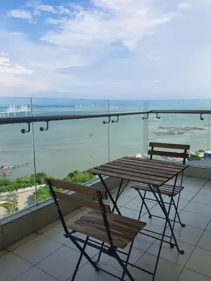 a table and chairs on a balcony with a view of the ocean at Southbay Seaview Condo A23 #10minQueensbay in Bayan Lepas