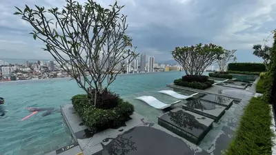 a pool of water with chairs and trees in it at Stunning 2BR with Infinity Pool & City Views in George Town