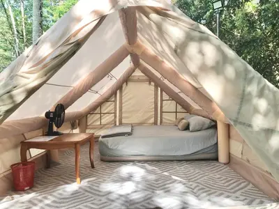 a bed in a canvas tent with a table at Glamping in Tapah