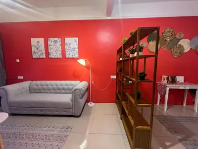 a living room with a couch and a red wall at RedHouse Sky Garden Klabang 10 pax in Chemor