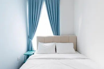 a bedroom with a bed with blue curtains at Royo Homestay in Palas Horizon in Brinchang