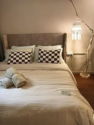 a bed with black and white pillows and a lamp at Senju Georgetown Heritage PrewarHouse 4BR 5-15 pax in George Town