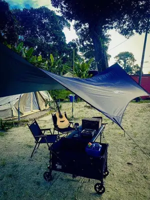 a tent and two chairs and a guitar in a field at Tok Mat Village & Adventure Park in Kampong Kepayang